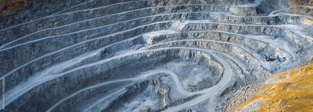 Wide panorama of open pit stone quarry with terraces, excavator and stone crusher machines