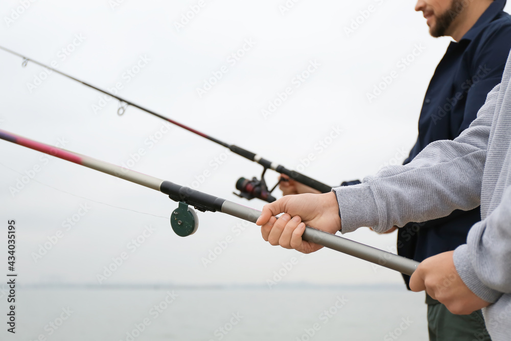 Father and son fishing together on river