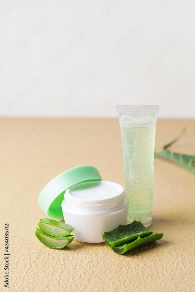 Cosmetic products with aloe leaves on color background