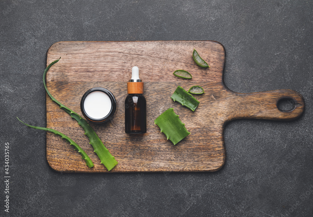 Cosmetic products with aloe leaves on dark background