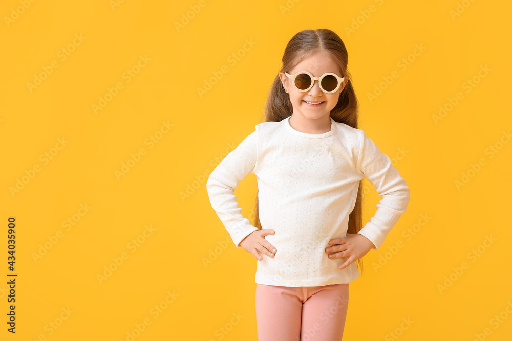 Cute little girl wearing stylish sunglasses on color background