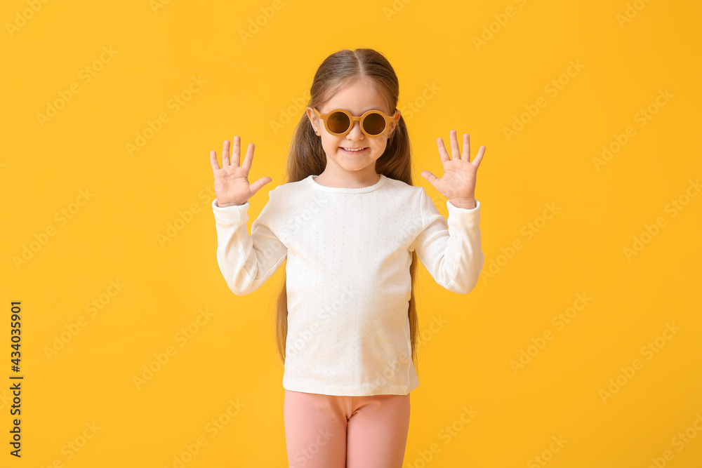 Cute little girl wearing stylish sunglasses on color background