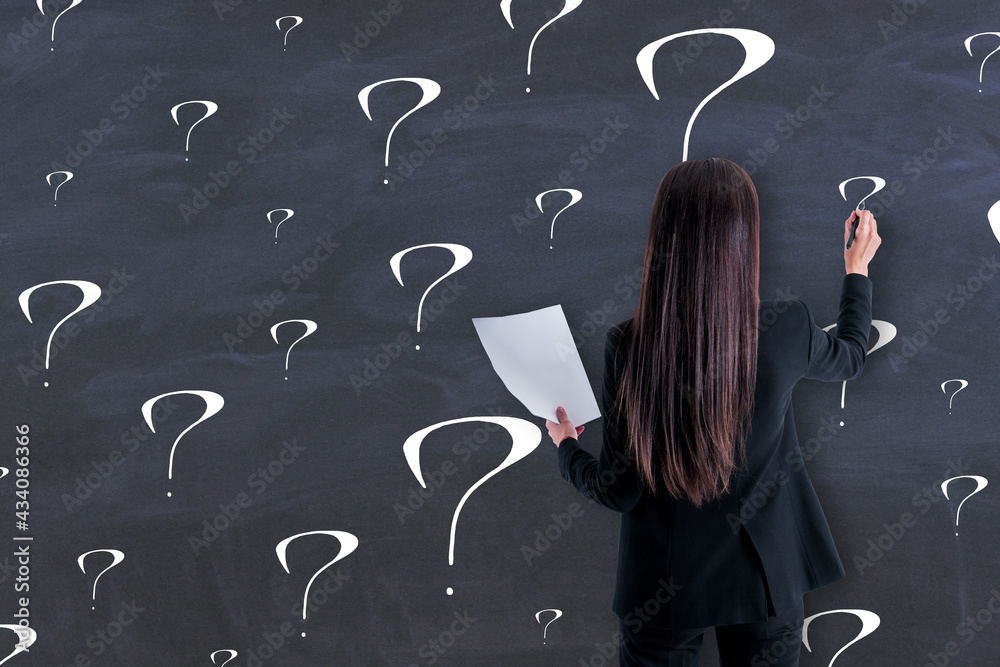 Business creative decision concept with back view on woman in black suit writing on chalkboard quest