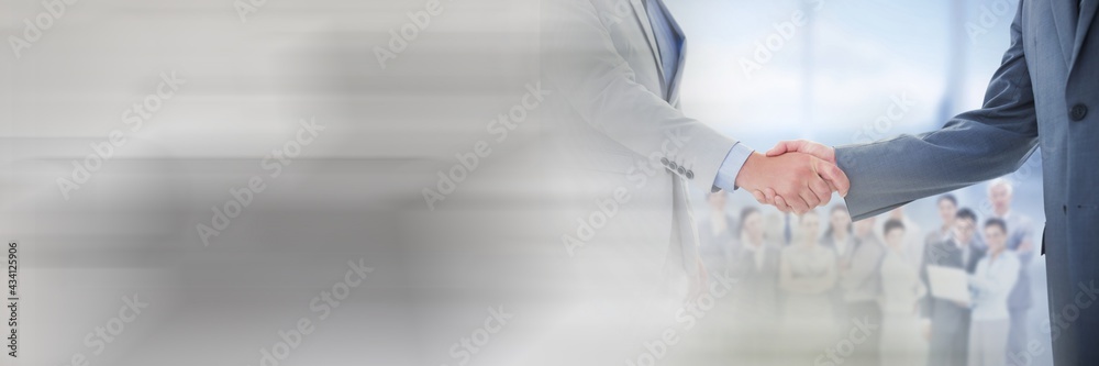 Two caucasian man having an handshake in front of colleagues