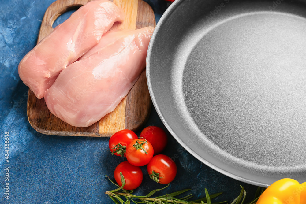 Clean frying pan with products on color background