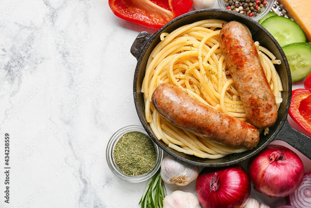 Frying pan with cooked sausages and pasta on table