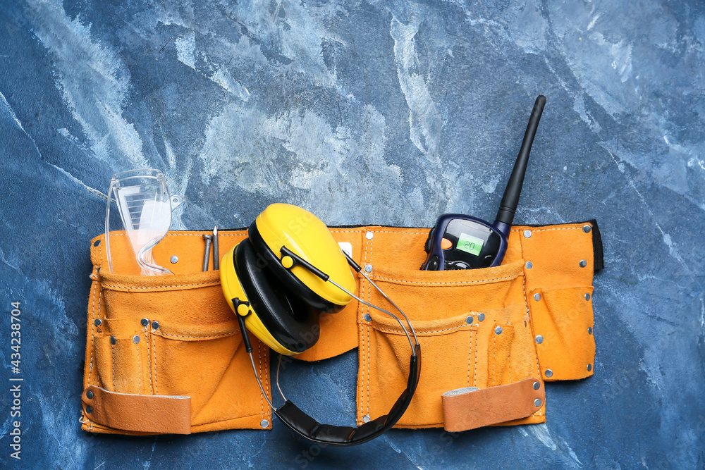 Bag with safety equipment on color background