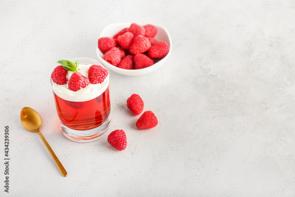 Glass of tasty raspberry jelly on light background