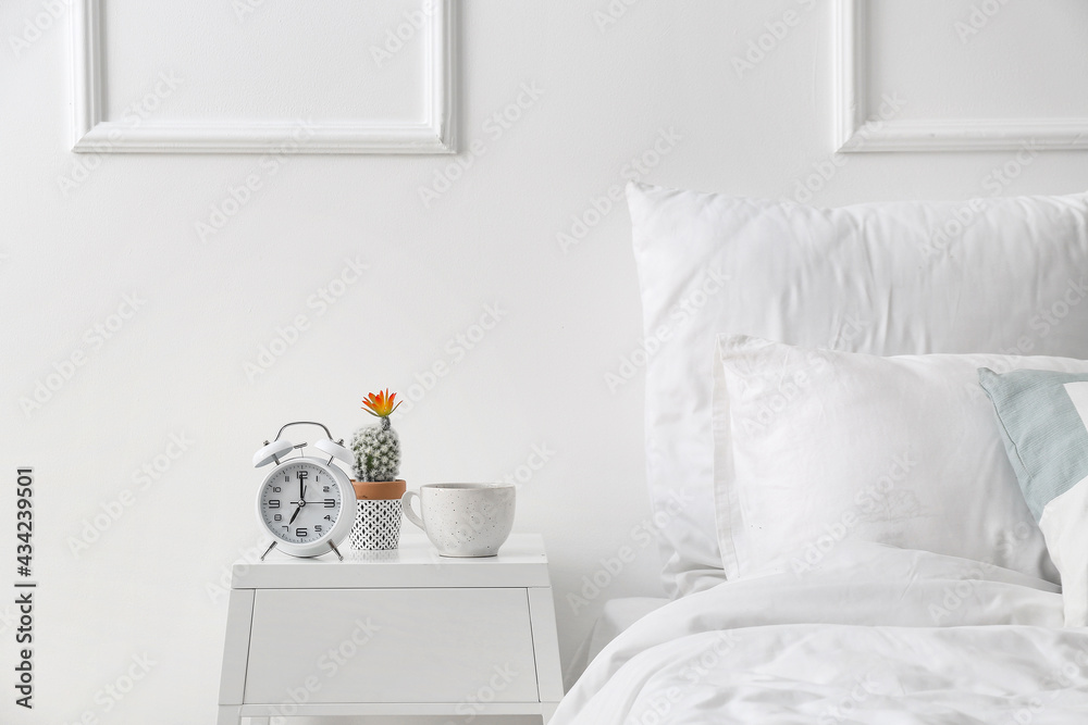 Alarm clock on table near light wall in bedroom