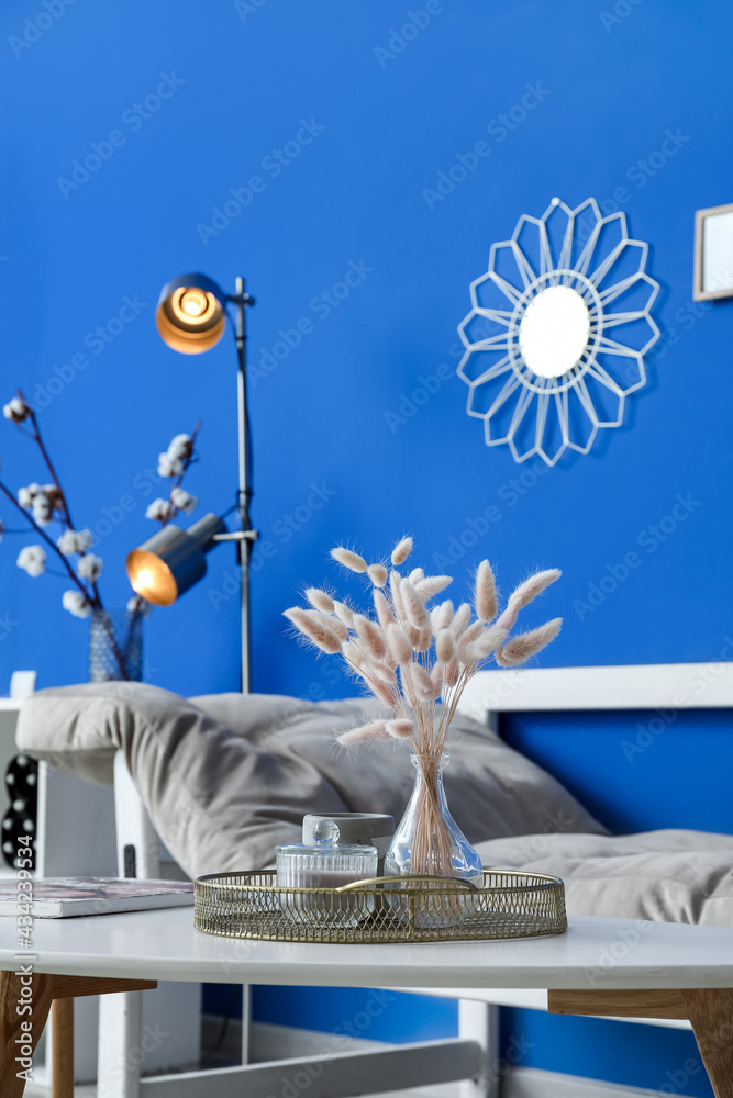 Vase with spikelets and candle on table in room