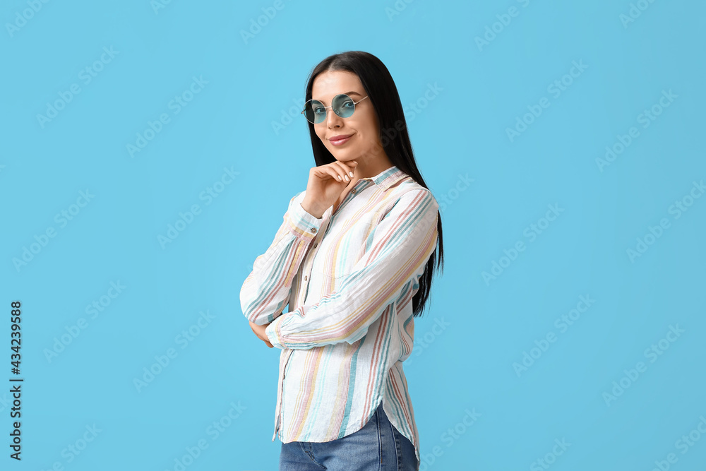 Beautiful young woman wearing stylish sunglasses on color background