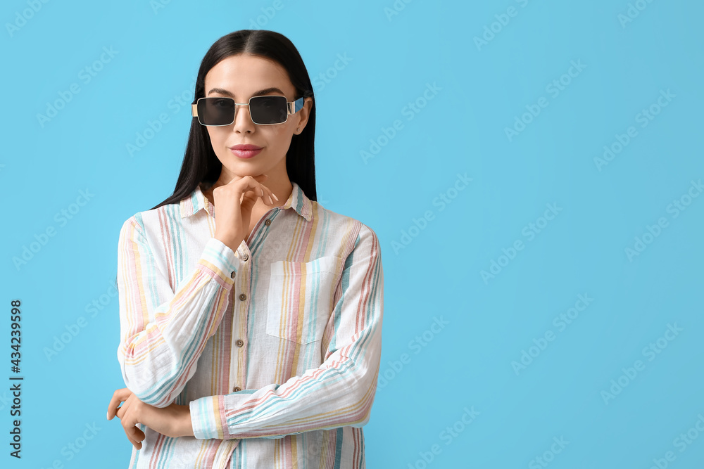 Beautiful young woman wearing stylish sunglasses on color background