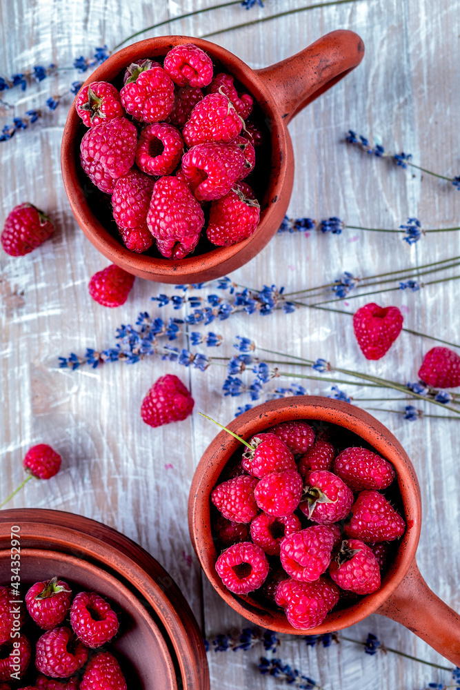 raspberry in pottery cup with lavender on wooden background top view