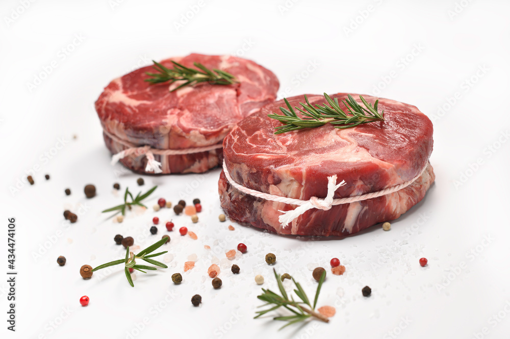 Fresh raw pieces of beef meat with ingredients for cooking in the kitchen on white table