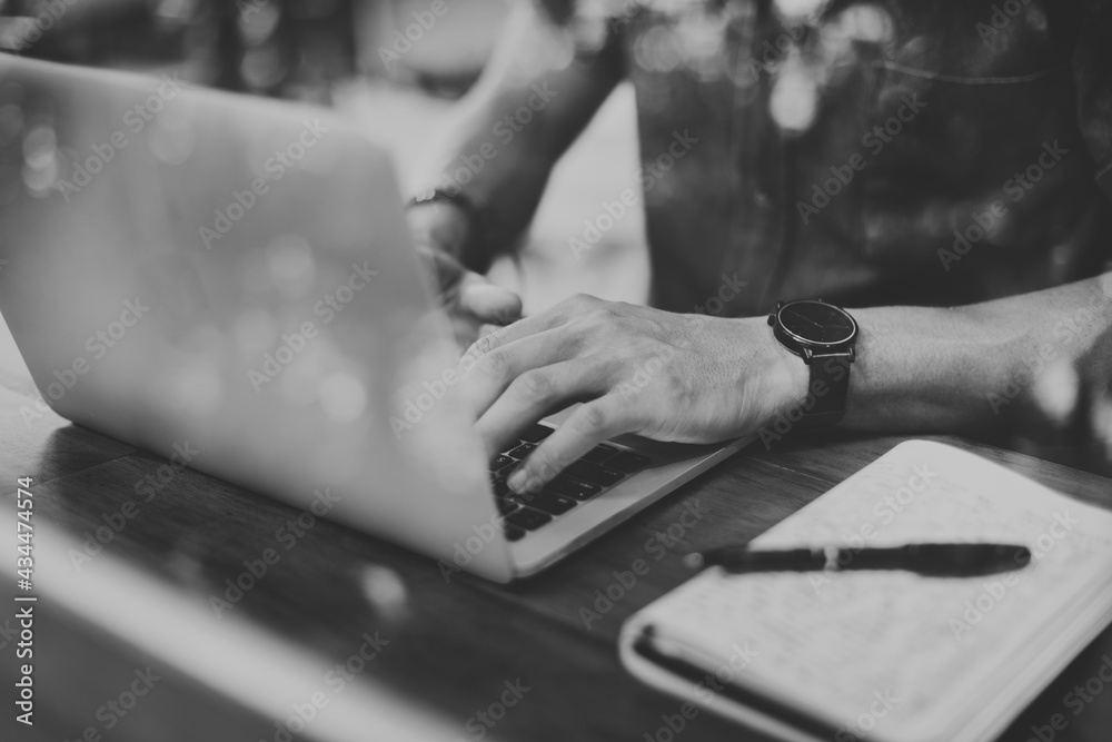 Closeup of man using laptop in cafe grayscale