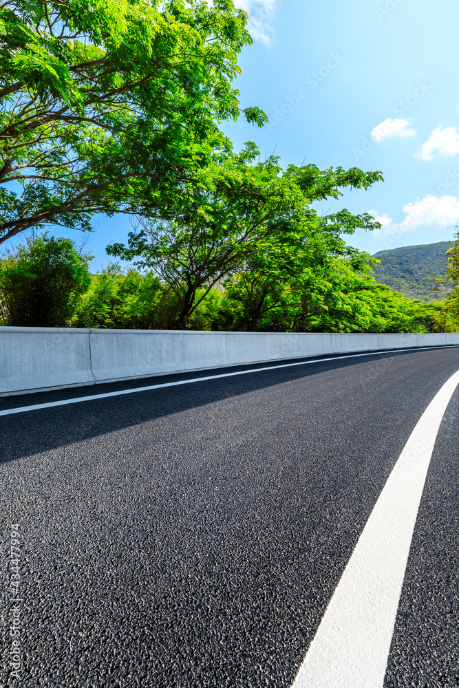 Asphalt road and green forest scenery.