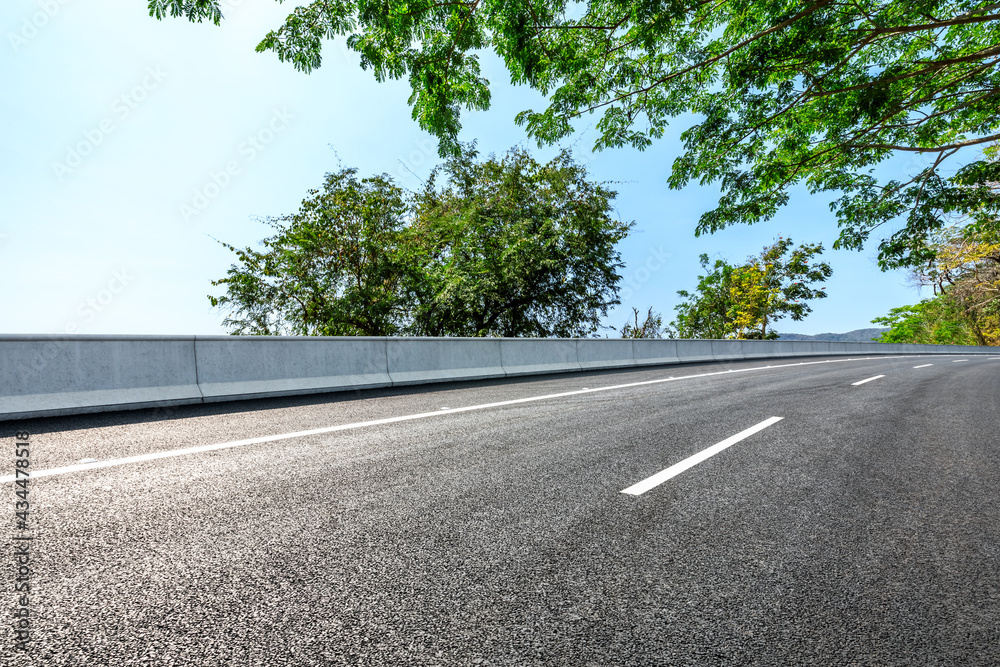 Asphalt road and green forest scenery.