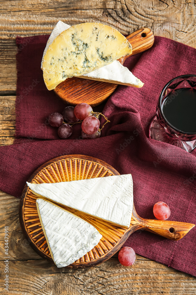 Glass of wine and tasty cheese on wooden background