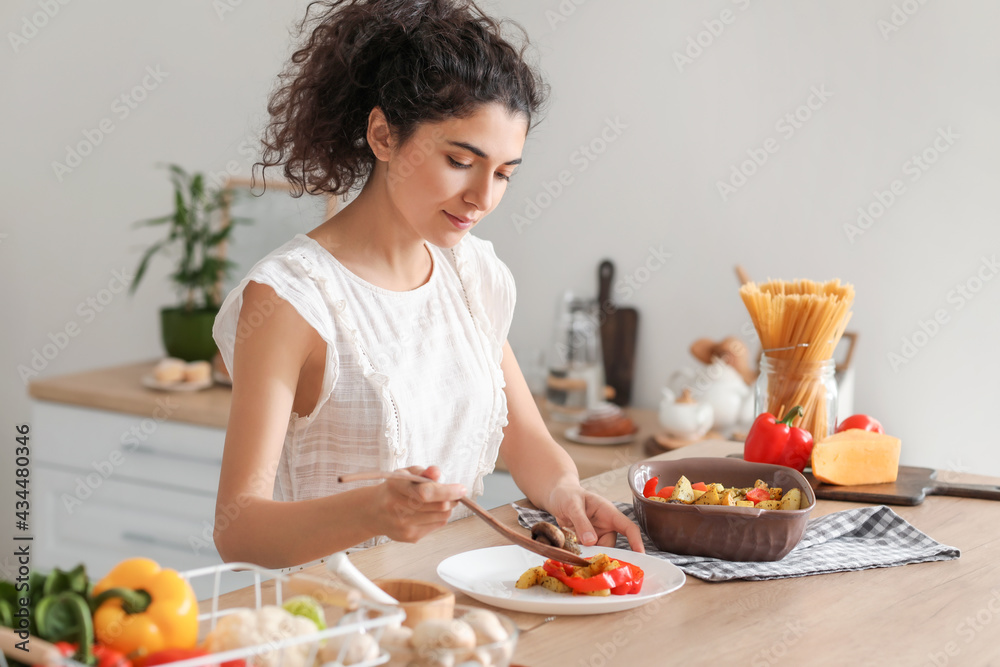 年轻女子在厨房把美味的菜放在盘子里