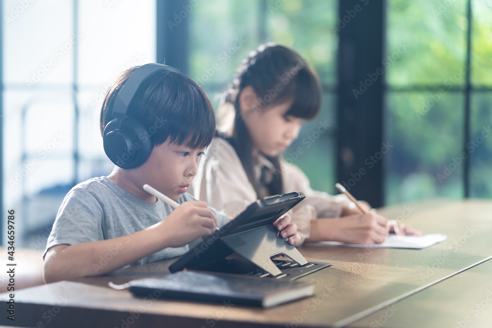 亚洲在家上学的男孩和女孩在家使用平板电脑在线学习。