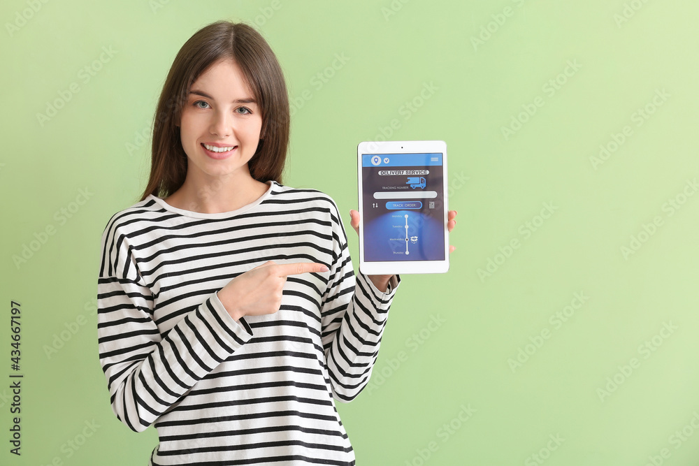 Woman pointing at tablet computer with open page of delivery service application on color background