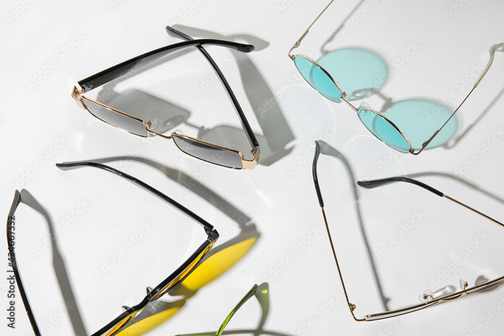 Different modern sunglasses on light background