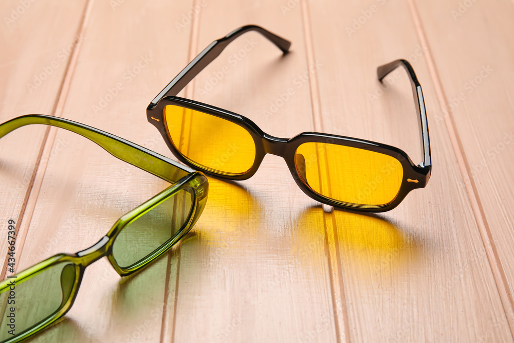 Different modern sunglasses on color wooden background, closeup