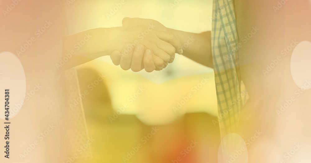 Composition of handshake with glowing yellow spots of light