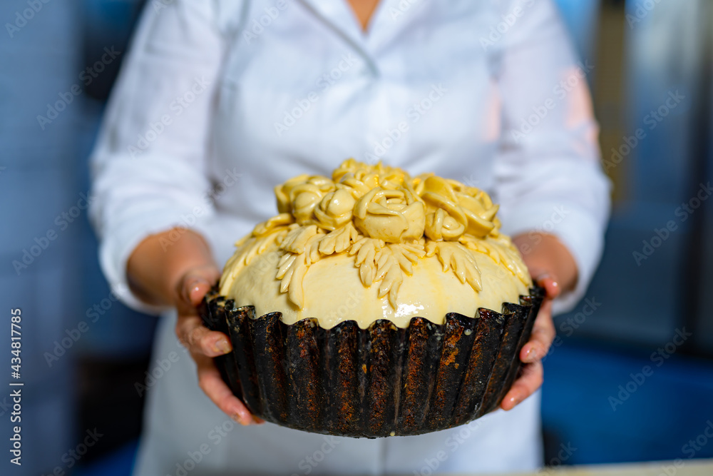 Fresh delicious cake in female baker hands. Tasty crusty bakery food.