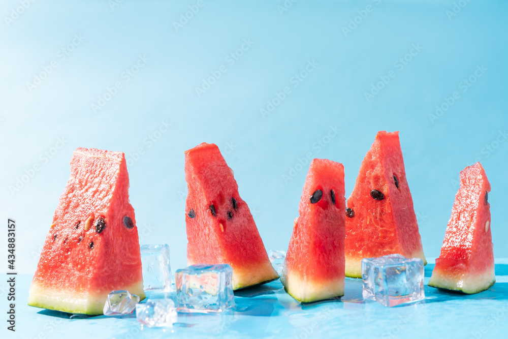 Fresh watermelon slices with ice cubes on a blue background