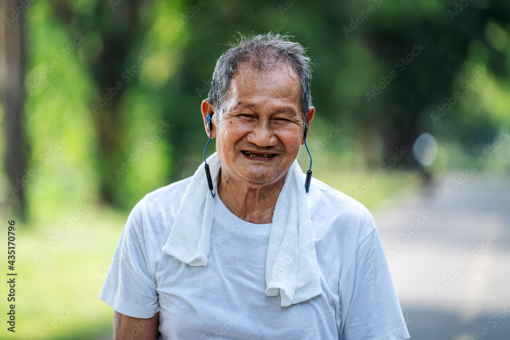 穿着健身服在公园跑步的亚洲老年男子的肖像。一个微笑的男子跑步的特写。