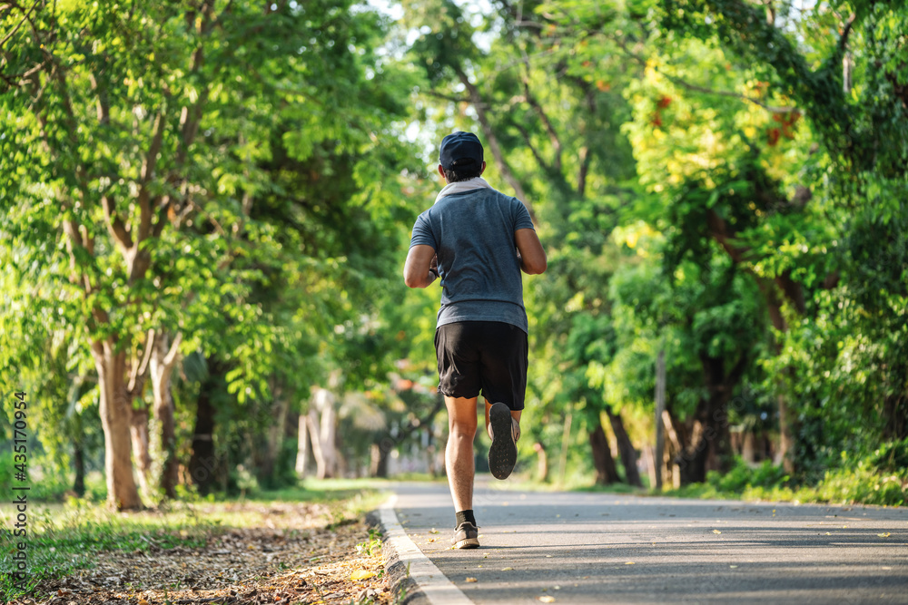 男子在公园户外慢跑或跑步锻炼的背影，健康生活方式的概念。