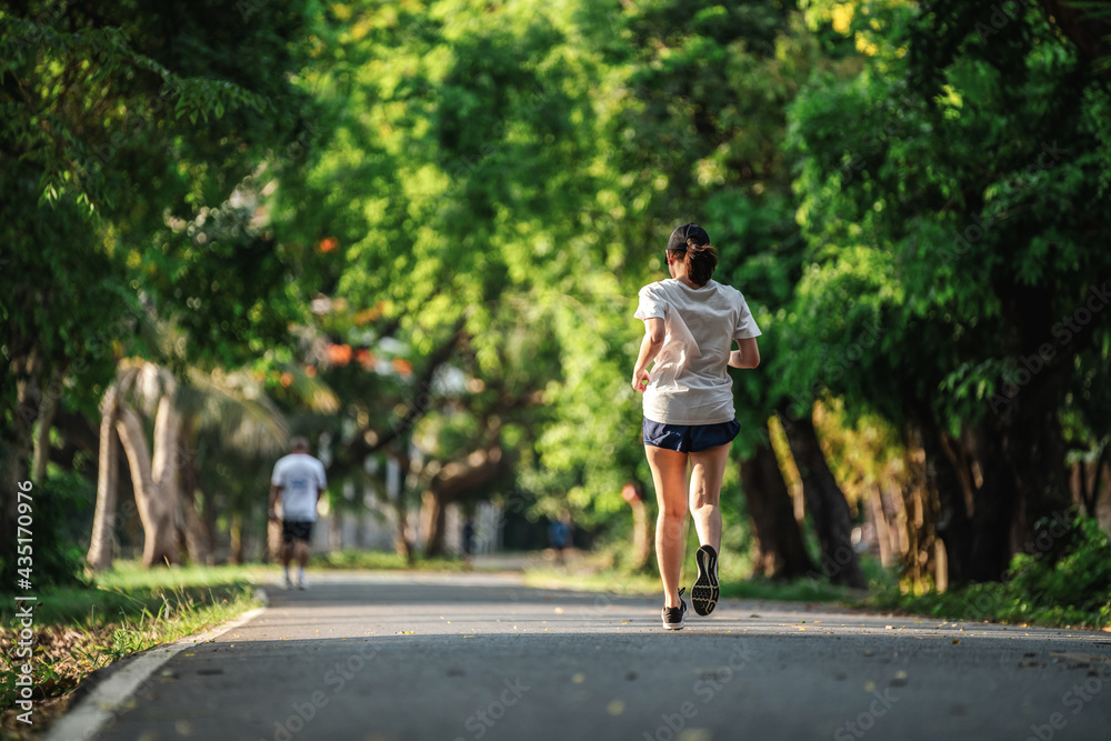 女性在公园户外慢跑或跑步锻炼的背影，健康生活方式的概念。