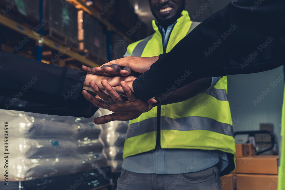 Factory workers stacking hands together in warehouse or storehouse . Logistics , supply chain and wa