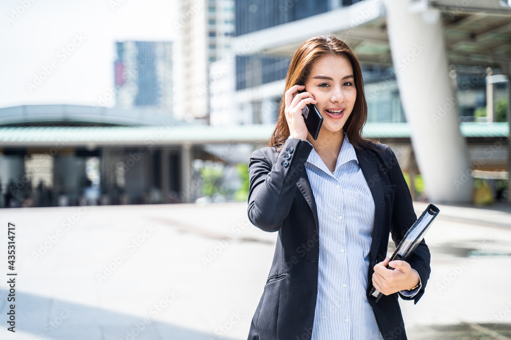 亚洲女商人在打电话，走到城市的办公室。