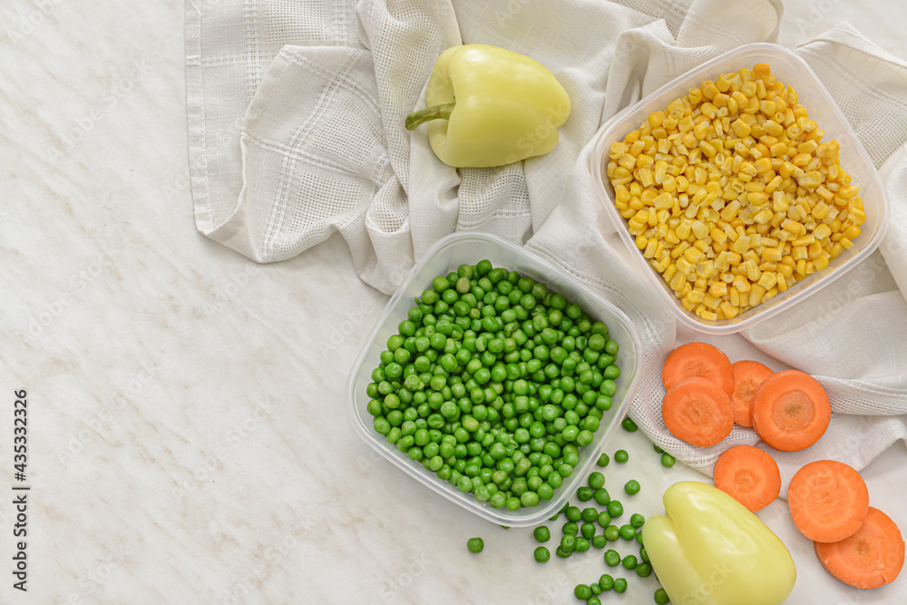 Plastic containers with vegetables on light background