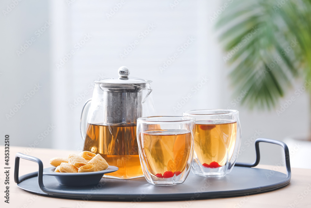 Teapot, glasses with hot tea and cookies on table in kitchen