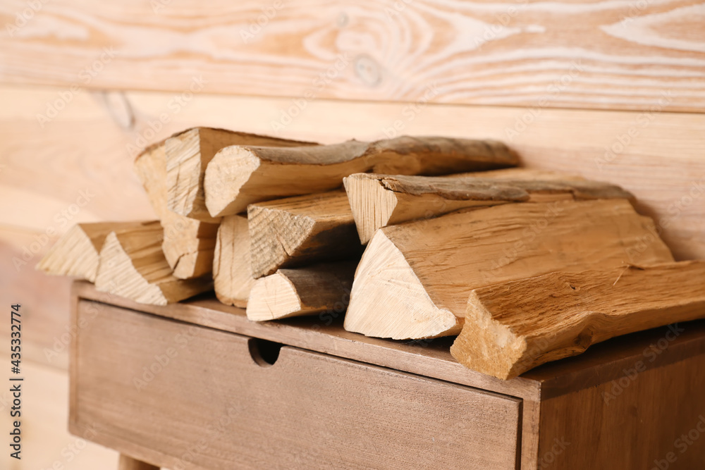 Table with firewood near wooden wall, closeup