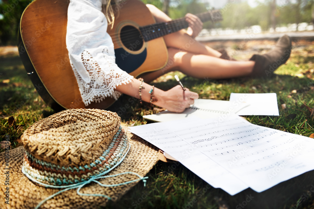 Closeup of woman guitarist sitting composing music in the park