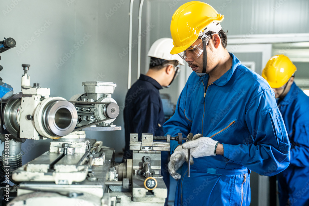 Asian male mechanical worker working on milling machine in workshop.