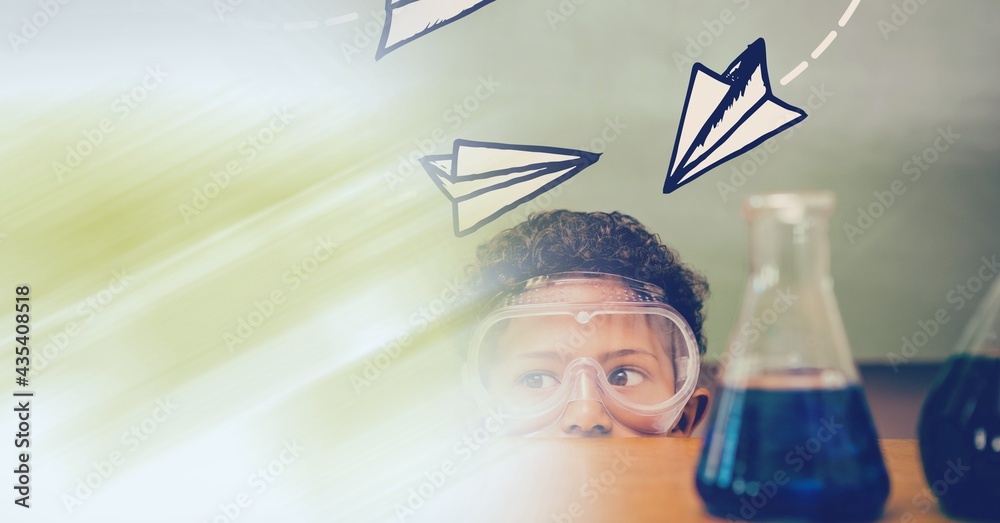 Composition of paper planes over schoolboy in protective glasses in school laboratory