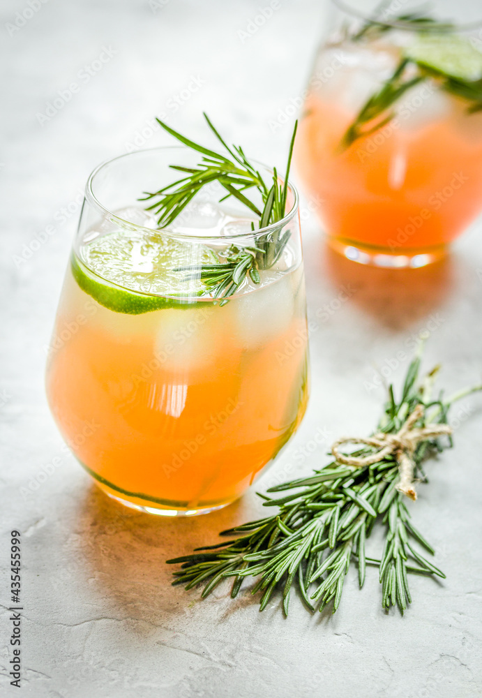 glass of fresh juice with lime and rosemary on stone table background