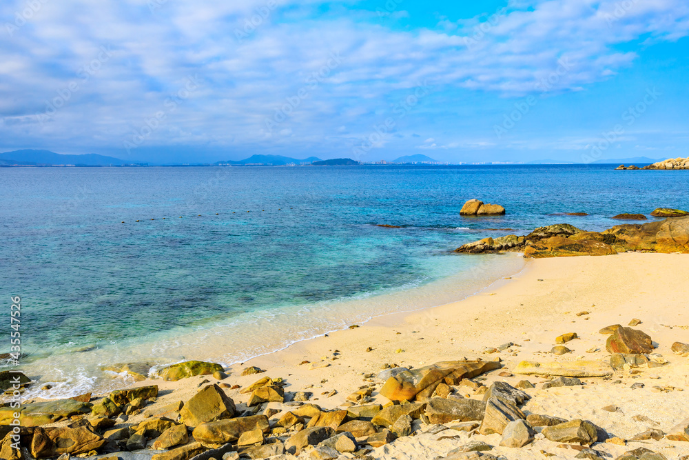 海滩、大海和蓝天上美丽的云朵的景观。海滩上的岩石。