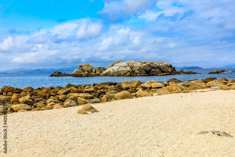 海滩、大海和蓝天上美丽的云朵的景观。海滩上的岩石。