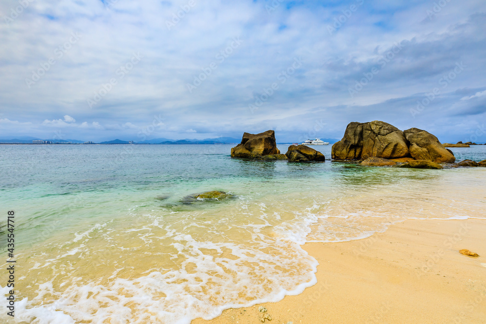 海滩、大海和蓝天上美丽的云朵的景观。海滩上的岩石。