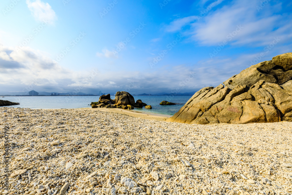 海滩、大海和蓝天上美丽的云朵的景观。海滩上的岩石。