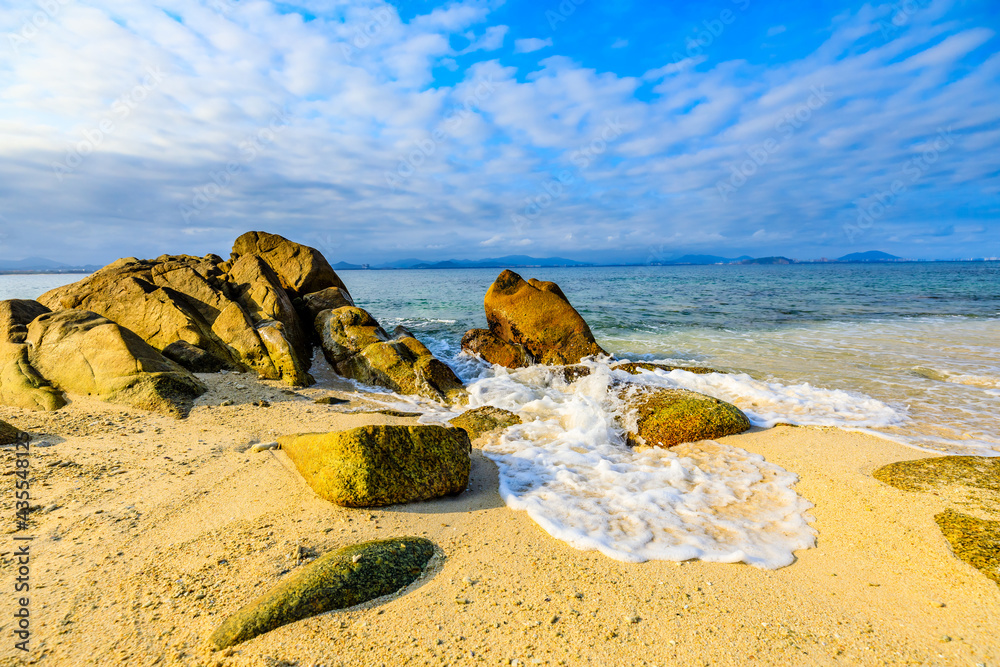 海滩、大海和蓝天上美丽的云朵的景观。海滩上的岩石。