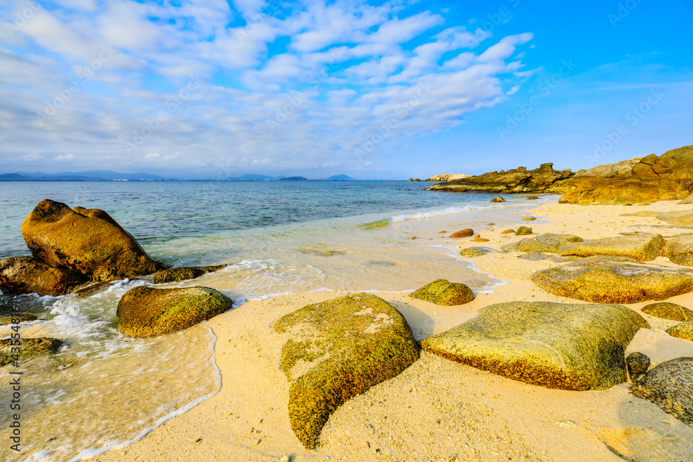 海滩、大海和蓝天上美丽的云朵的景观。海滩上的岩石。