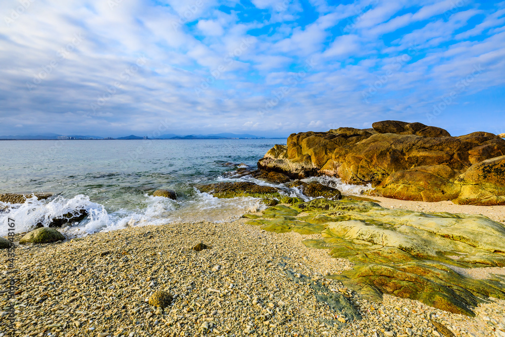 海滩、大海和蓝天上美丽的云朵的景观。海滩上的岩石。