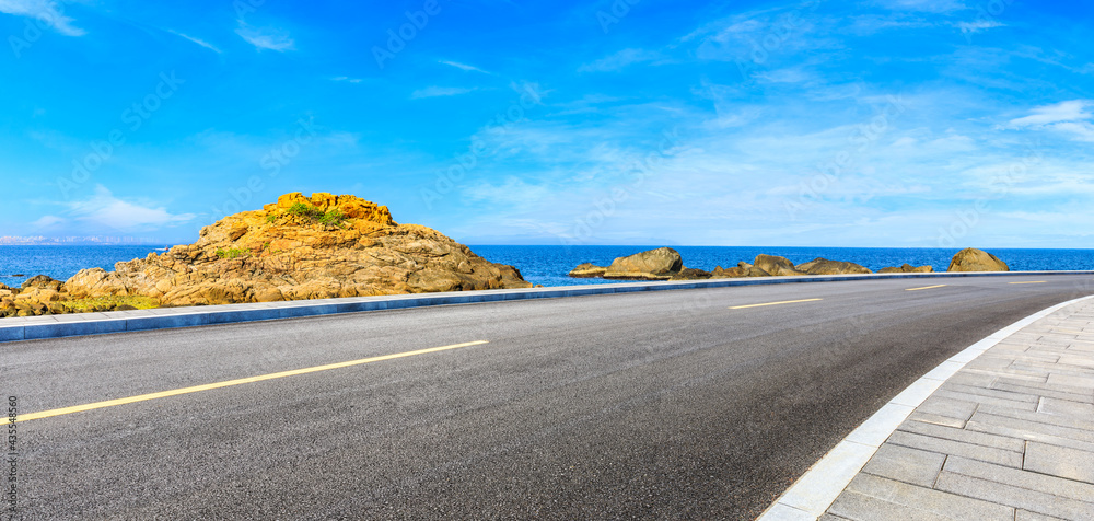 Asphalt road and beautiful seaside scenery under blue sky.